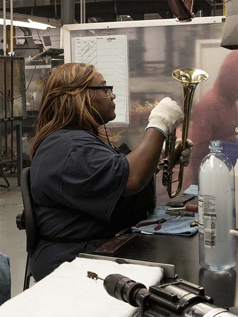 woman cleaning a trumpet assembly