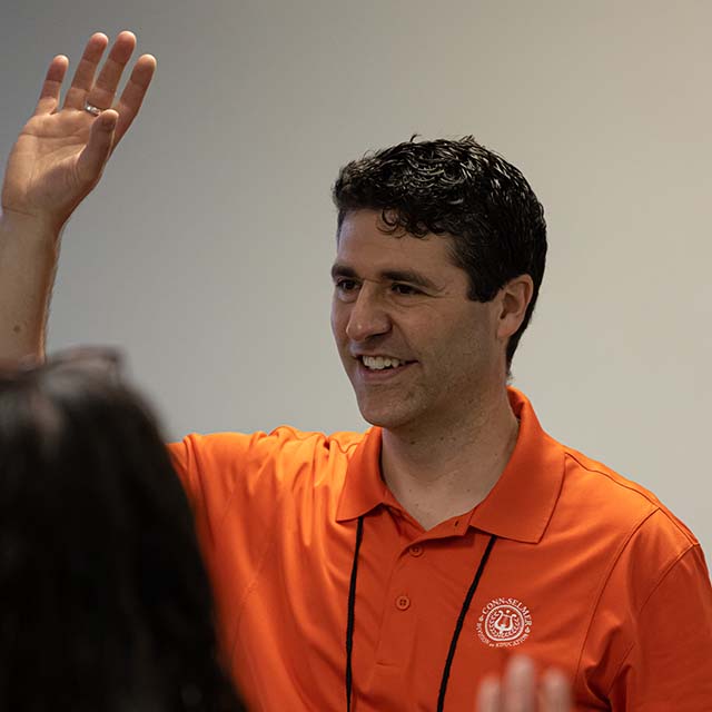 Dr. Matt Arau holding his hand up in class